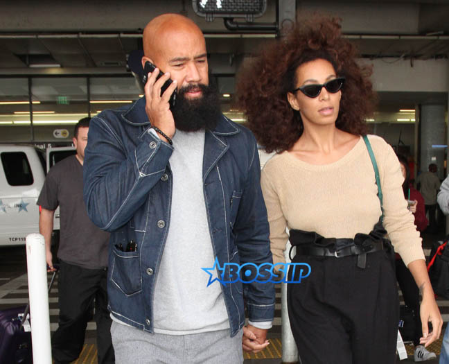 Solange Knowles husband, Alan Ferguson at LAX with highwater pants, camel-toe shoes and a beige top. SplashNews beard denim jacket white sneakers holding hands