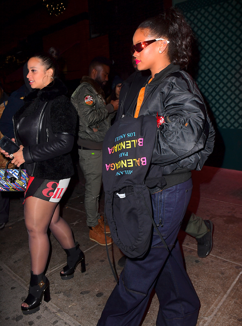 Rihanna leaving Avenue Nightclub early Saturday futuristic pair of Dior Sunglasses which she designed joined by OITNB star, Dascha Polanco, in a tight red and yellow dress. Rihanna covered her "engagement ring" w/ her Balenciaga hoodie as she walked out surround by security