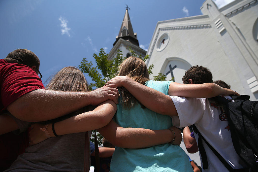 CHARLESTON, SC - JULY 17: A church youth group from Douthan, Alabama prays in front of the Emanuel AME Church on the one-month anniversary of the mass shooting on July 17, 2015 in Charleston, South Carolina. Visitors from around the nation continue to pay their respects at a makeshift shrine in front of the church, in a show of faith and solidarity with "Mother Emanuel", as the church is known in Charleston. Nine people were allegedly murdered on June 17 by 21-year-old white supremacist Dylann Roof, who was captured by police in North Carolina the following day. He is scheduled to go to trial July 11, 2016.