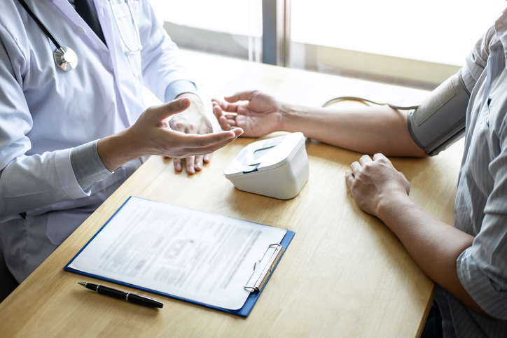 Midsection Of Doctor Examining Patient At Desk In Hospital