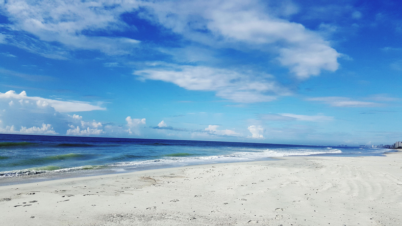 Scenic View Of Beach Against Blue Sky
