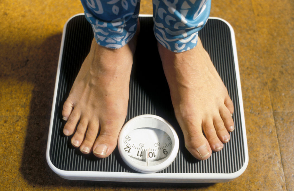 Woman weighing herself on scales.