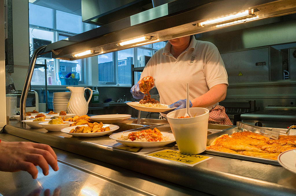 A woman serving food in a school canteen, Wales UK