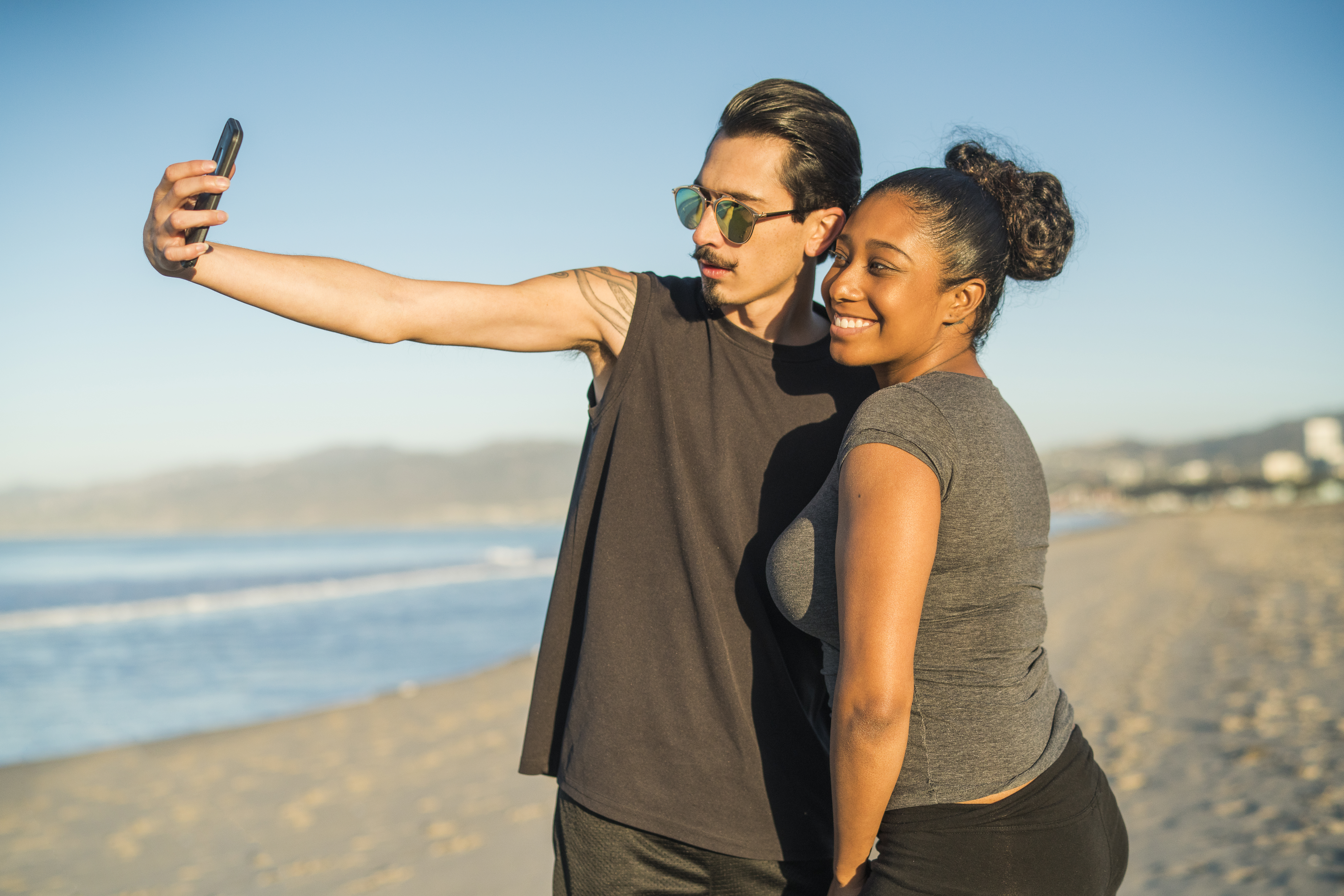 Young couple, Latino man and girl, take selfie on beach