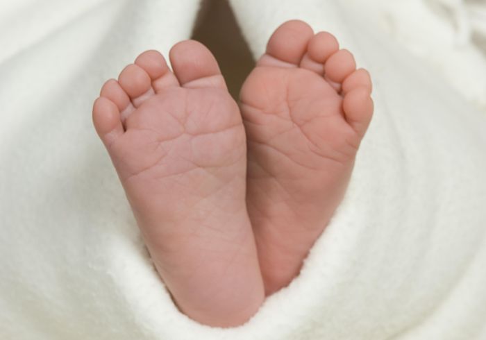 Pair of baby's feet poking out from blanket, close-up