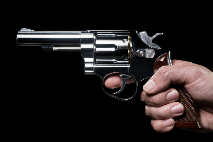 Cropped Hand Of Man Holding Gun Against Black Background