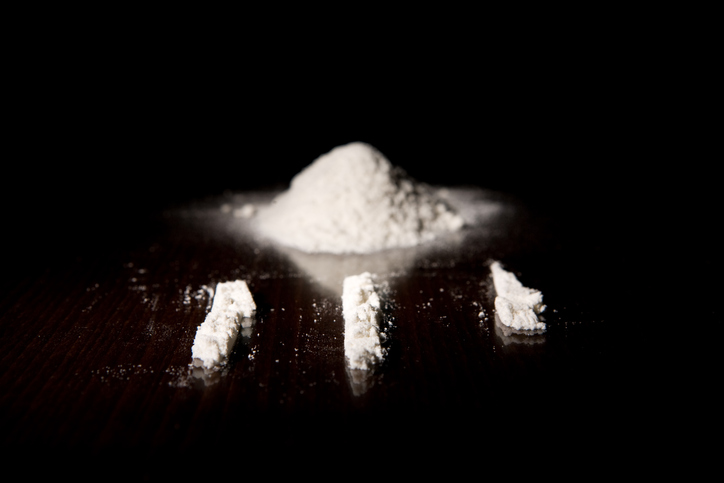 Three lines of cocaine next to a pile of it