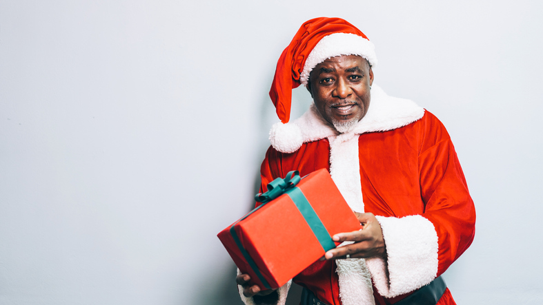 Santa Claus holding christmas gift on grey background