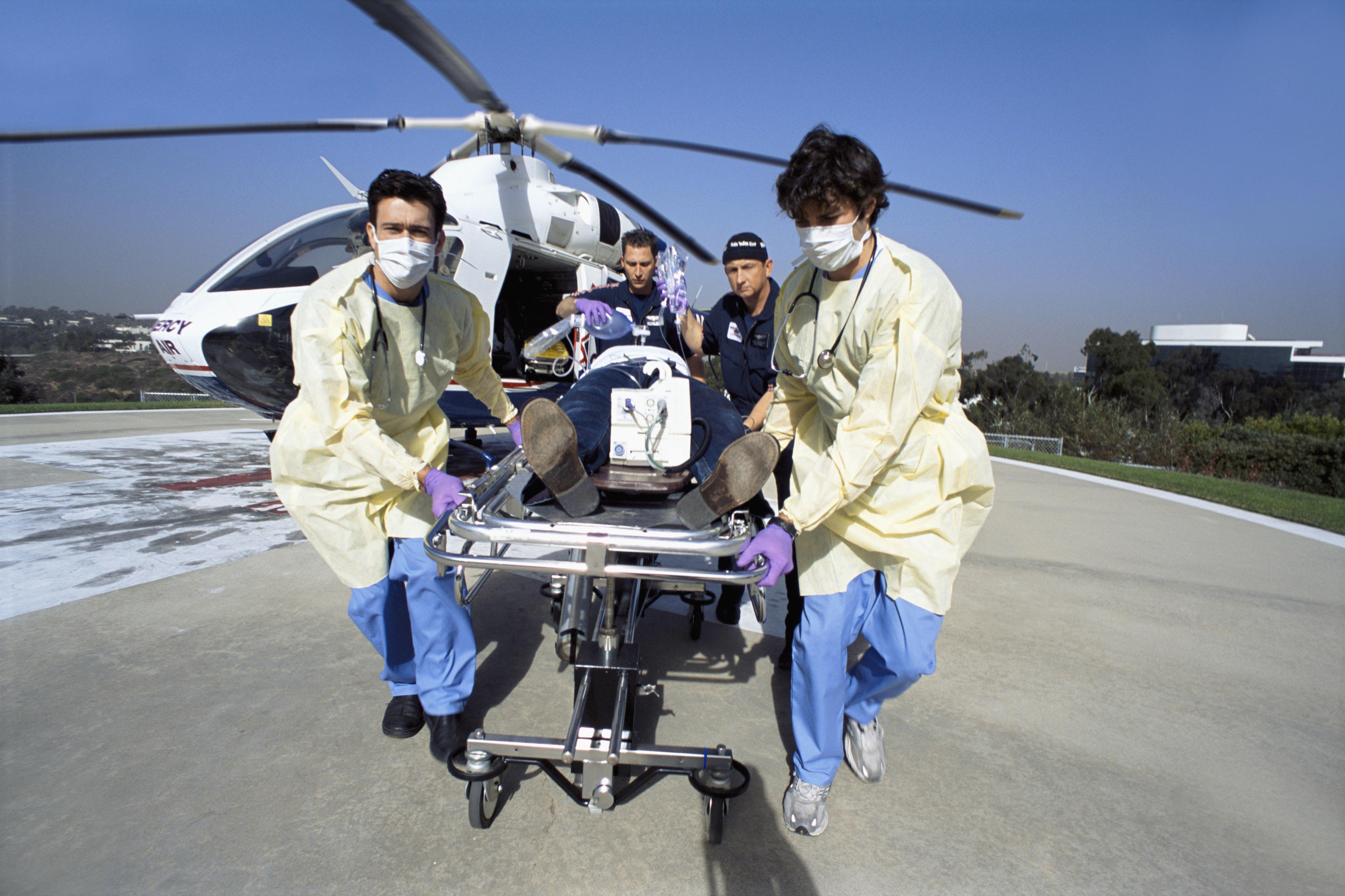 Doctors and paramedics rushing patient on gurney from emergency airlift helicopter
