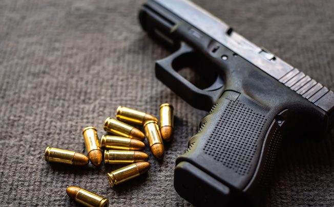 Close-Up Of Gun With Bullets On Table