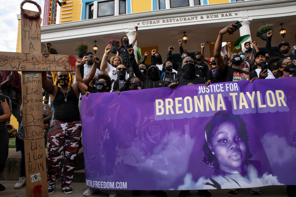 Protesters stand in front of a local Cuban restaurant while...