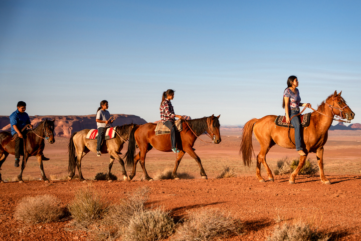 Four Young Native American Navajo Brothers and Sisters Riding their Horses Bareback in the Northern Arizona Monument Valley Tribal Park At Dusk Together