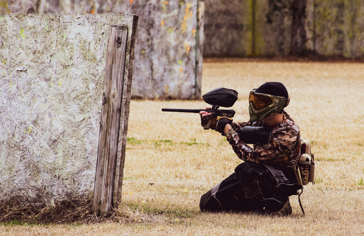 Man Crouching With A Paintball Gun