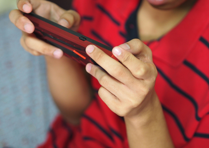 Asian Boy sitting hold mobile play game, used technology