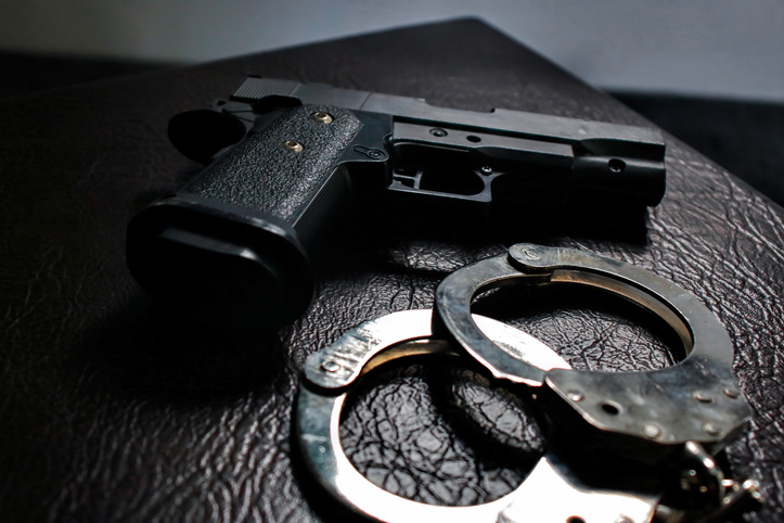 Metal handcuffs and gun on the Leather sofa. criminal justice