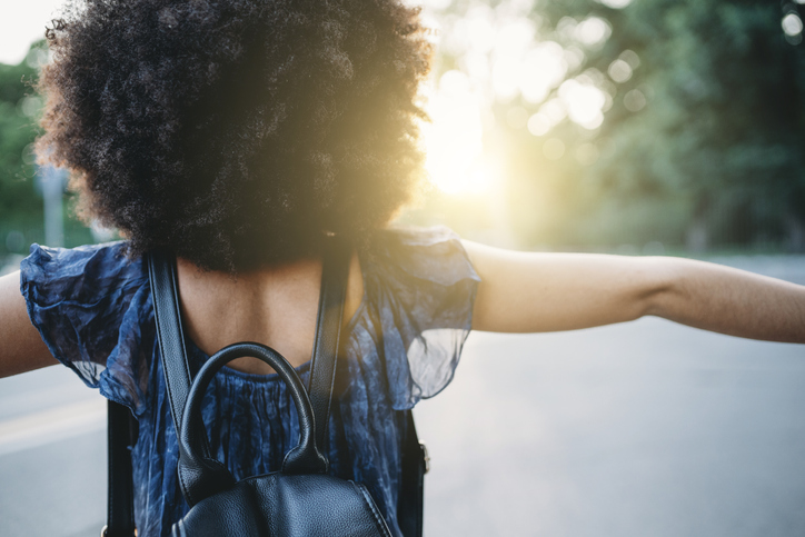 Young adult woman feels free in the city at sunset