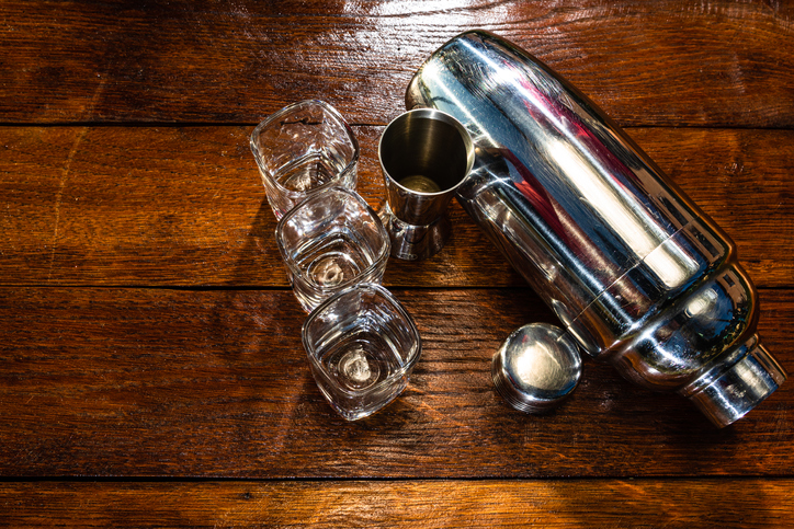 Top view of cocktail shaker set, bartender utensils kit on a rustic wooden table; drinking concept