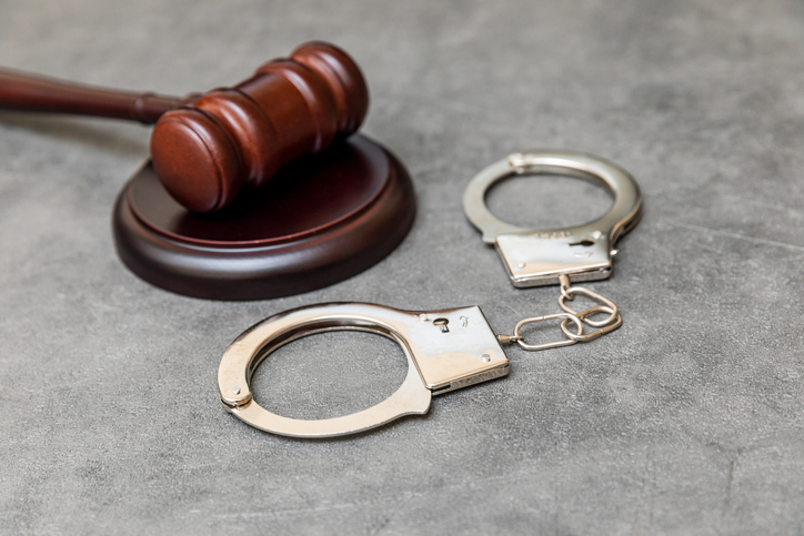 Law theme. Court of law trial in session. Judge gavel handcuffs on grey table in lawyer office or court session. Mallet of judge on concrete stone grey background. Justice human rights concept.