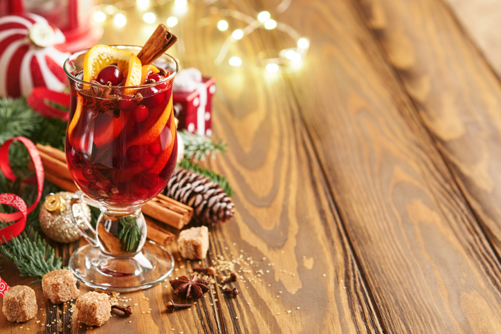 Christmas hot mulled wine. Glasses of mulled wine with aromatic spices cinnamon, anise, sugar and fir tree branches with bokeh and decorations. Traditional Xmas festive drink. Winter Christmas drink.