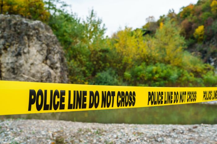 police line do not cross on the yellow tape securing crime scene in nature near the river on the beach no people copy space
