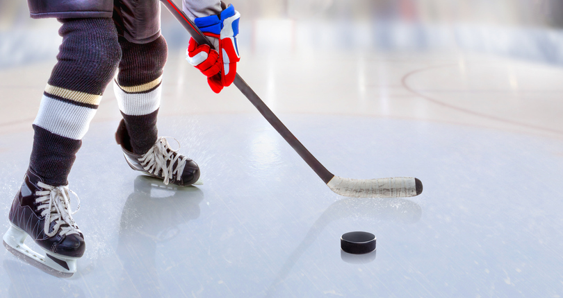 Close up of ice hockey player with stick on ice rink controlling puck