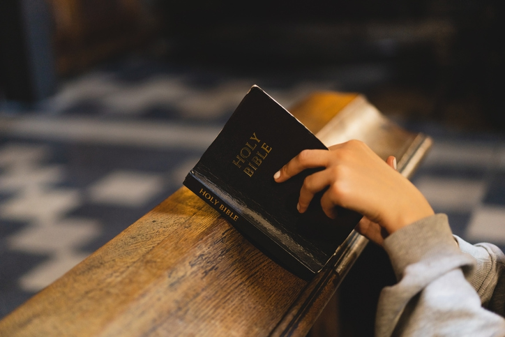 Christian woman reading bible in an ancient Catholic temple