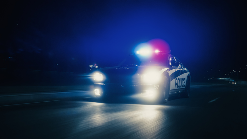 Traffic Patrol Car In Pursuit, Driving Fast with Sirens Blazing through the City Streets. Officers of the Law Chasing a Suspect. Cops in Squad Car React to Emergency Call. Cinematic Night Shot
