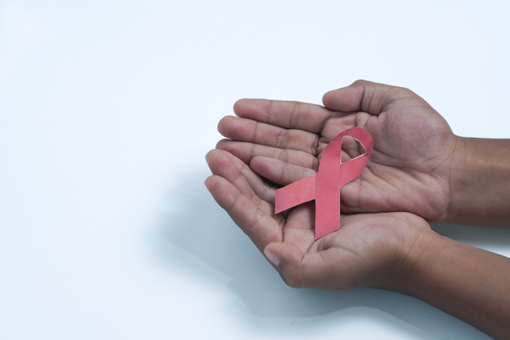 child cupped hands holding red ribbon for HIV AIDS. HIV awareness concept, world AIDS day concept