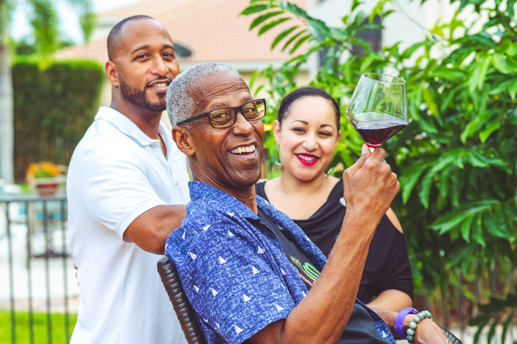 Happy family outdoors on a patio enjoy glasses of wine and togetherness