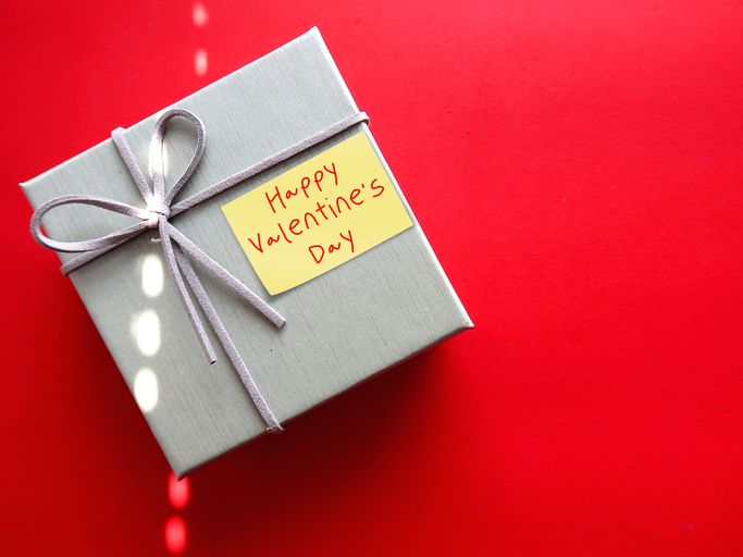 Gift box on red copy space baclground with handwritten text HAPPY VALENTINE 'S DAY, concept of express romantic love and make someone feel special on Valentines's day