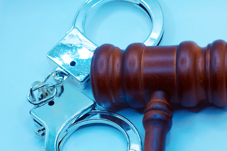 Metal handcuffs, book and judge gavel.