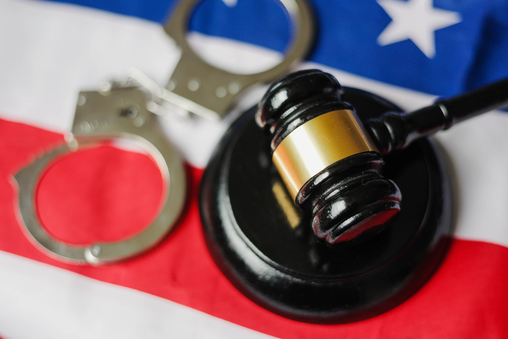 Gavel and handcuffs over american flag. Concept of criminal and punishment.