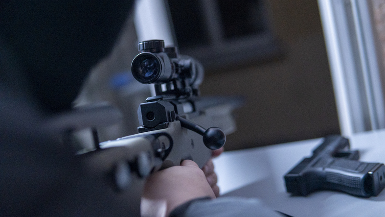 The masked killer is aiming a sniper rifle