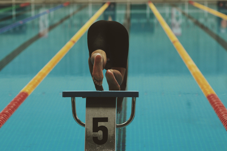 Rear View Of Swimmer Jumping In Pool