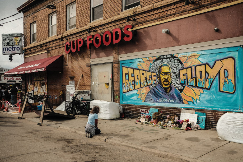 A woman pays respect to a mural of George Floyd by the Cup...