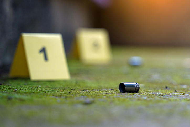 Bullet casings fell on the moss growing on the cement floor and blurry background of the evidence number plate at the scene. Concept of investigation, forensic science.