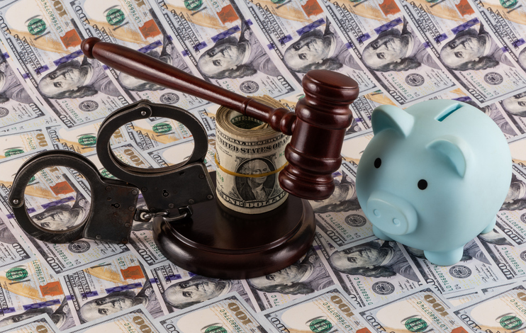 Handcuffs and a judge's gavel against a background of $100 bills