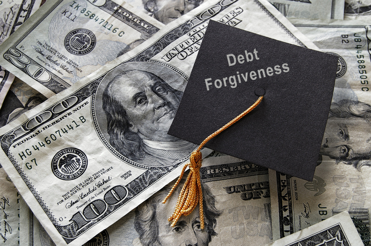 Debt Forgiveness text on mini graduation cap with cash