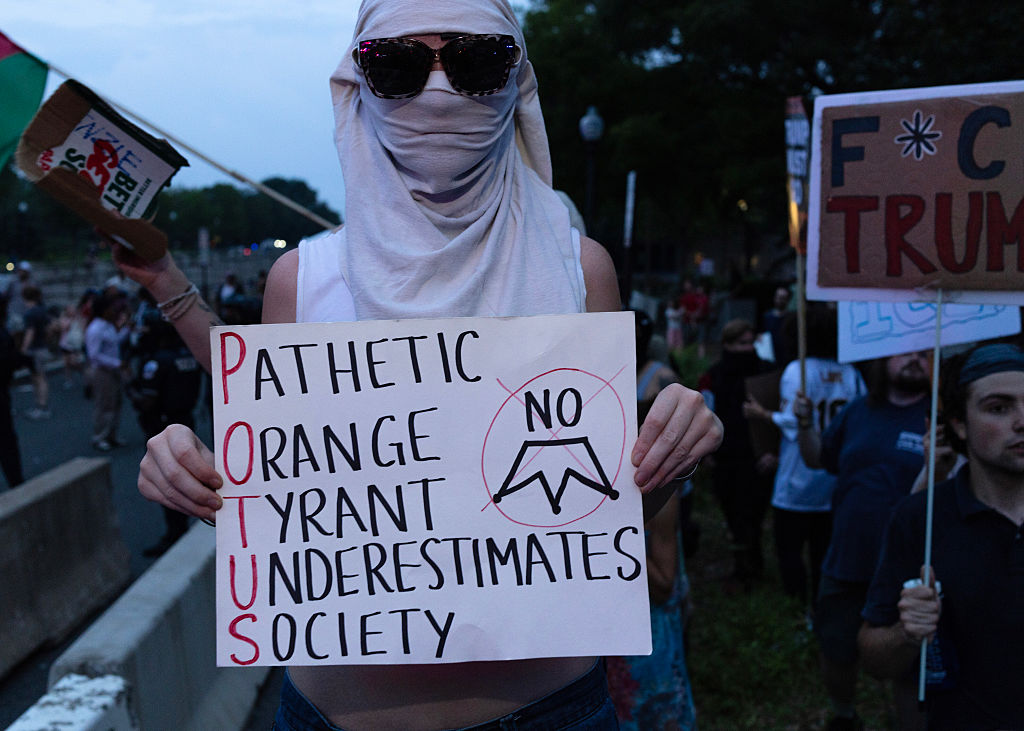 Protesters holding anti-Trump signs gather near the National...