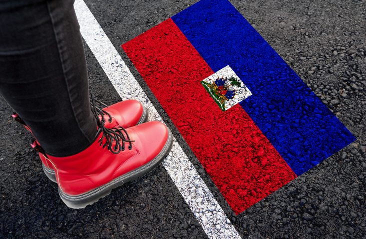 a woman standing next to flag of Haiti