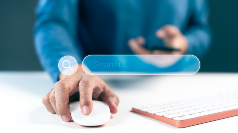 Hand Using Computer Mouse with Search Bar Interface on Screen – Online Search Concept