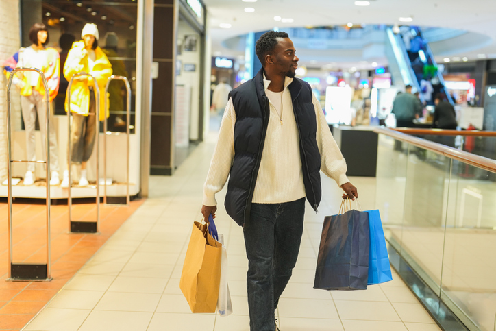 African American Man Shopping in a Modern Mall with Multiple Bags